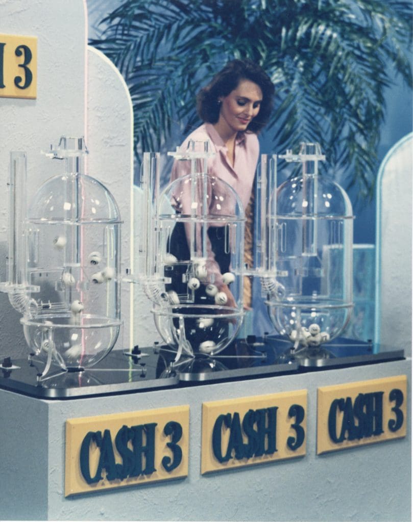 A woman standing behind cash 3 lottery machines