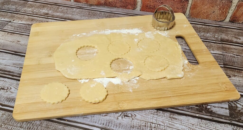 Dough with flour and cut out circles on top of a cutting board.