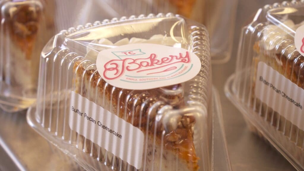A cake on a plastic case with TC BAkery label.  On the side it says Butter Pecan Cheesecake.