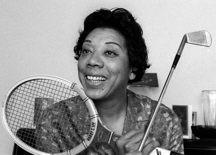 Althea Gibson is smiling while holding a racket