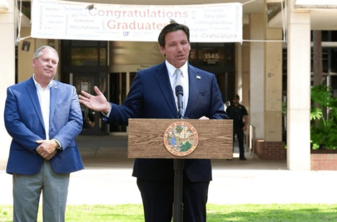 Ron DeSantis in a suit standing in front of a building