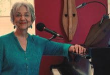 The Vibes of Velma Frye Velma Fyre poses next to microphone and piano