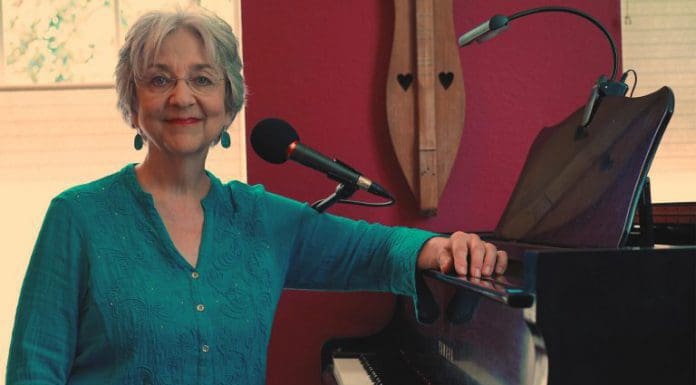 The Vibes of Velma Frye Velma Fyre poses next to microphone and piano