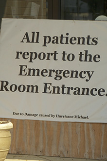sign in front of medical facility that reads - all patients report to the emergency room entrance due to damage caused by Hurricane Michaelr