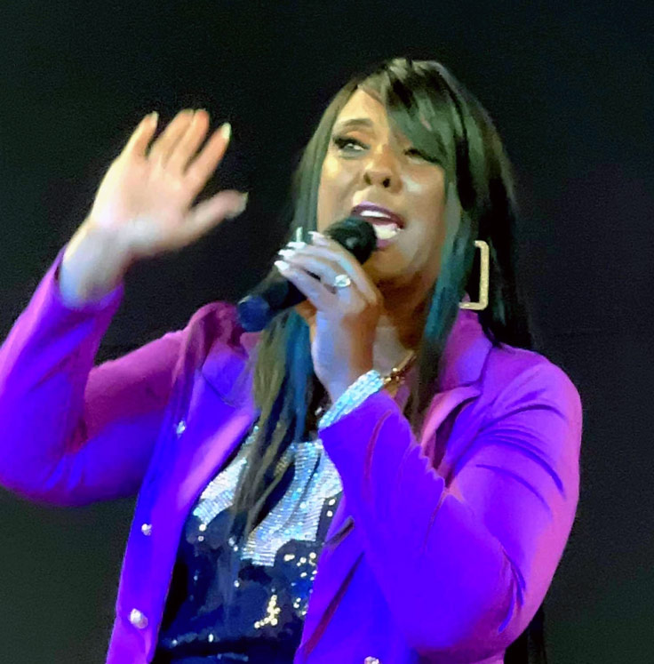 woman in purple singing in a mic