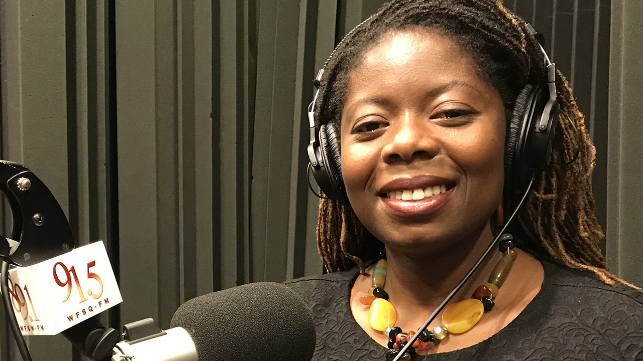 Abena sitting in the studio by the microphone with headphones on