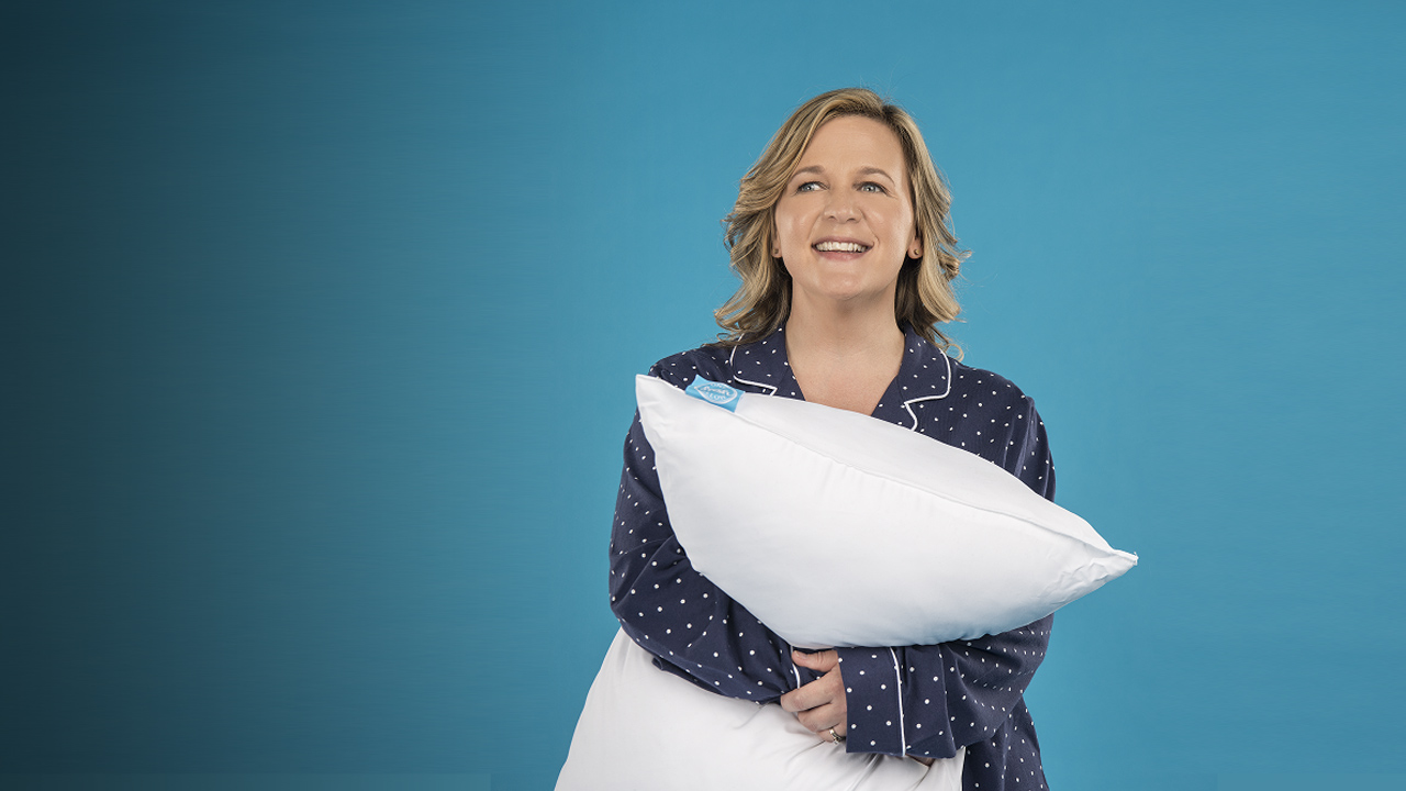 woman smiling and holding a pillow