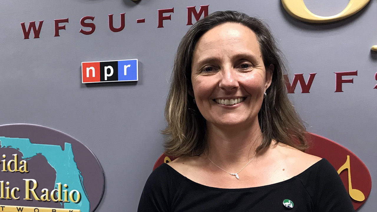 Aliki smiling in front of the WFSU radio station sign