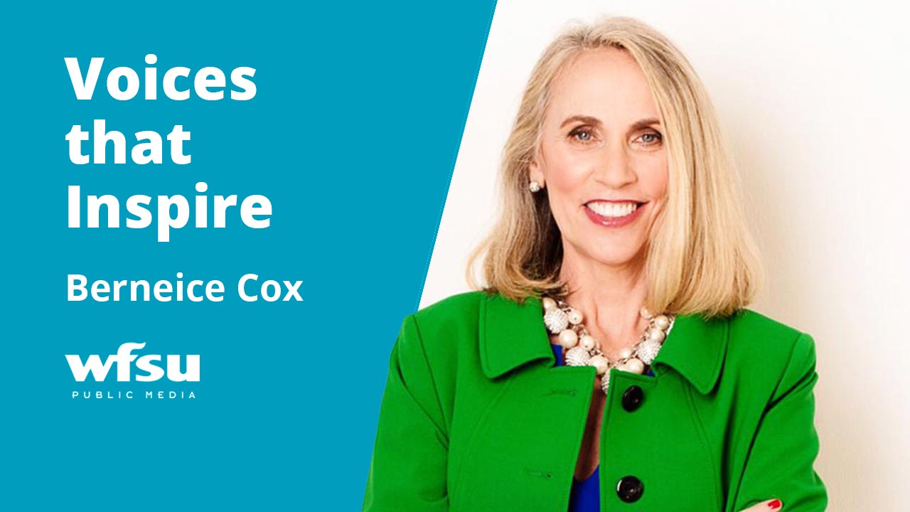 A smiling woman dressed in green and blue stares forward.