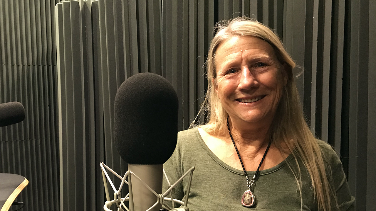 Carol in front of the microphone smiling