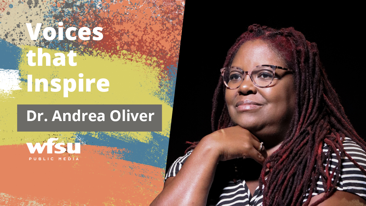 A smiling woman sits in front of a black background.