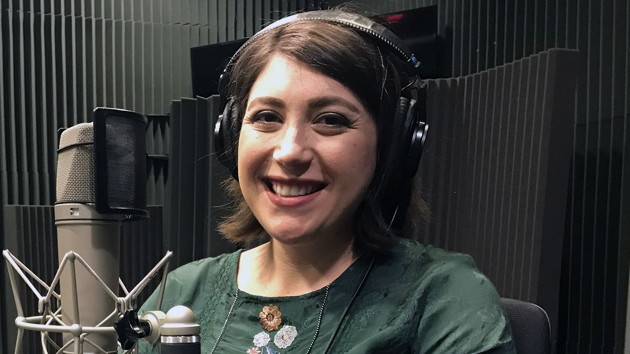 woman smiling, wearing headphones, in sound-proofed room
