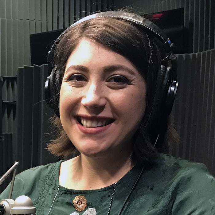 woman smiling, wearing headphones,  in sound-proofed room 