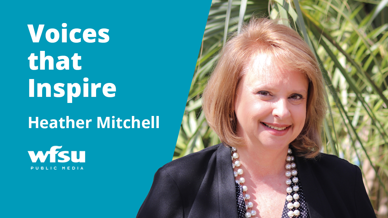 A woman in a blazer is smiling outside.