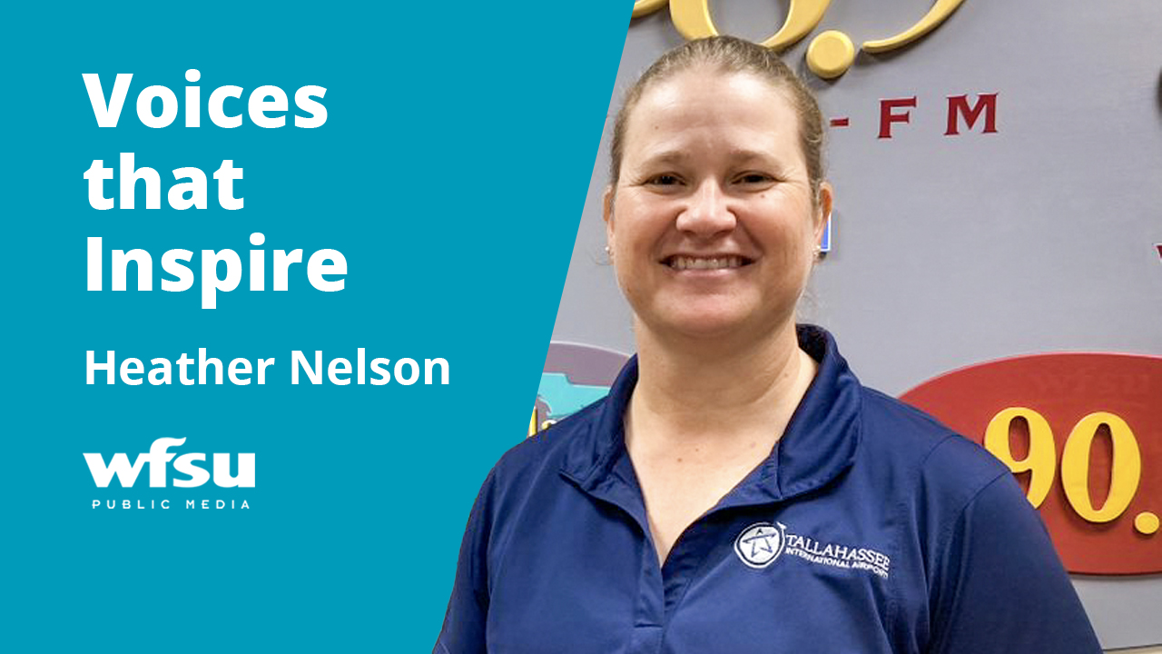 A smiling woman in a blue shirt smiles.