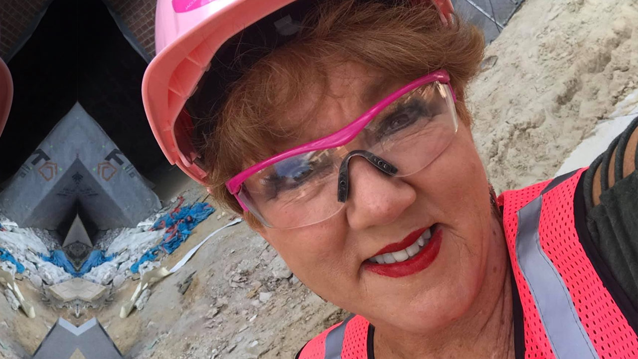 Woman smiling in pink hard hat.