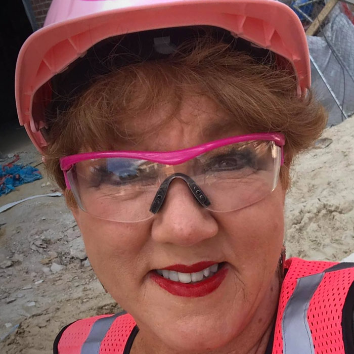 Woman smiling in pink hard hat.