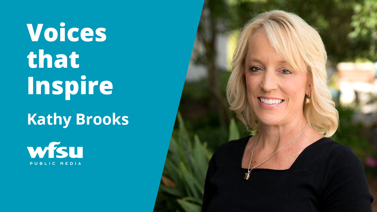 Woman in a black dress smiling outside.