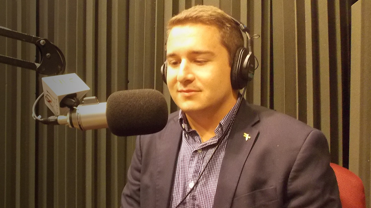 Kyle Baltuch sitting in WFSU's radio studio in front of the mic