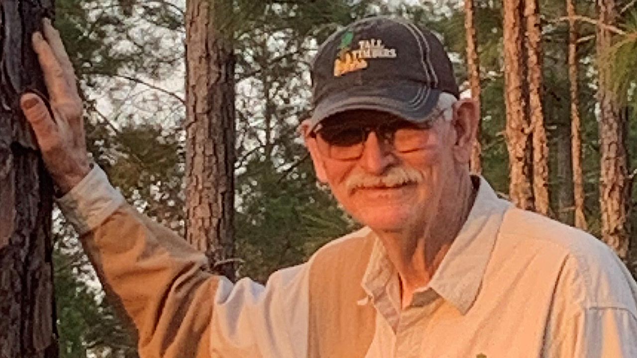 Man in a baseball cap in a forest.