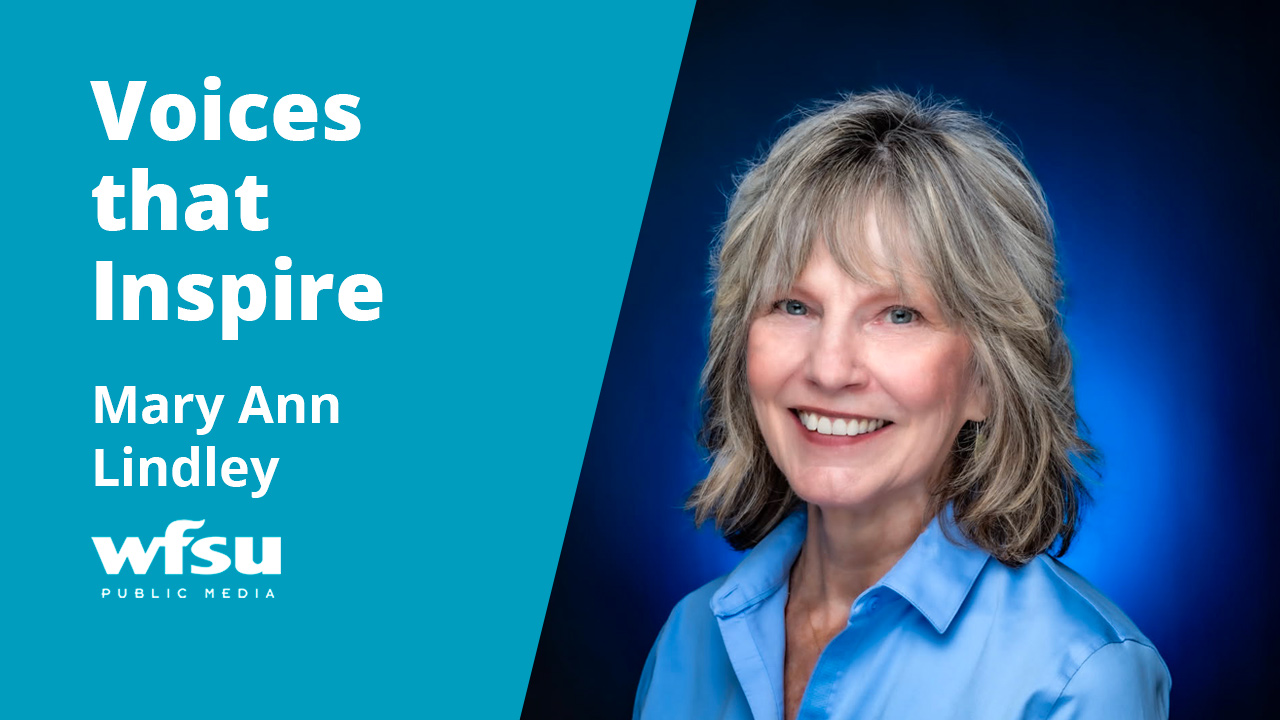A smiling woman stands in front of a blue background.