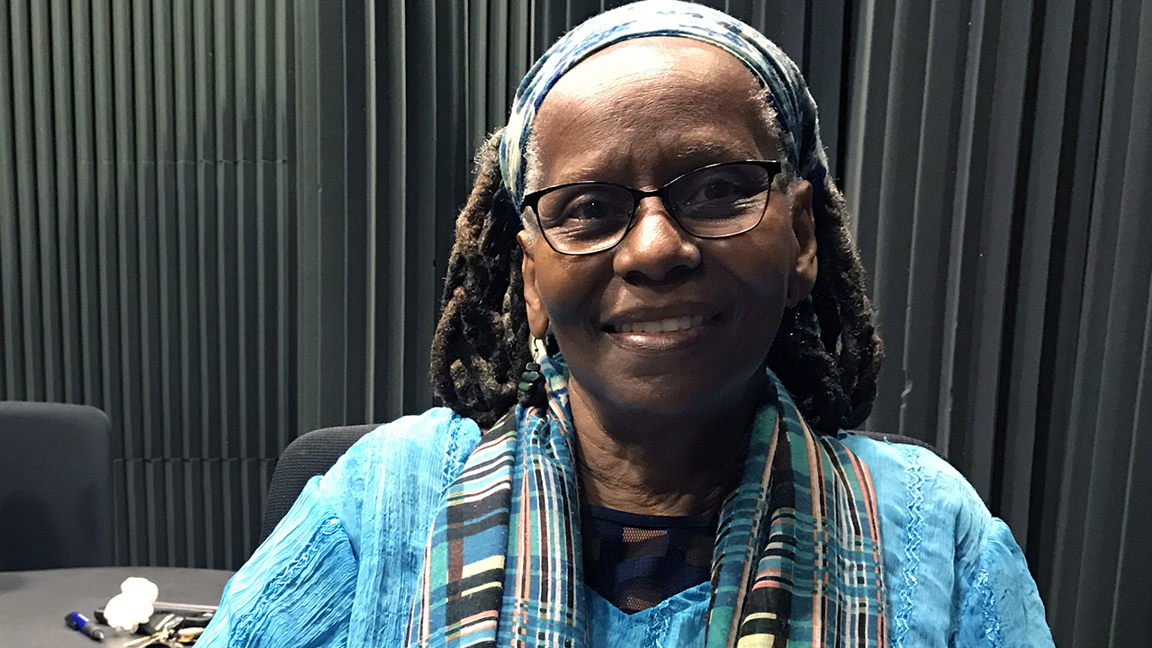 woman in blue, wearing glasses, smiling