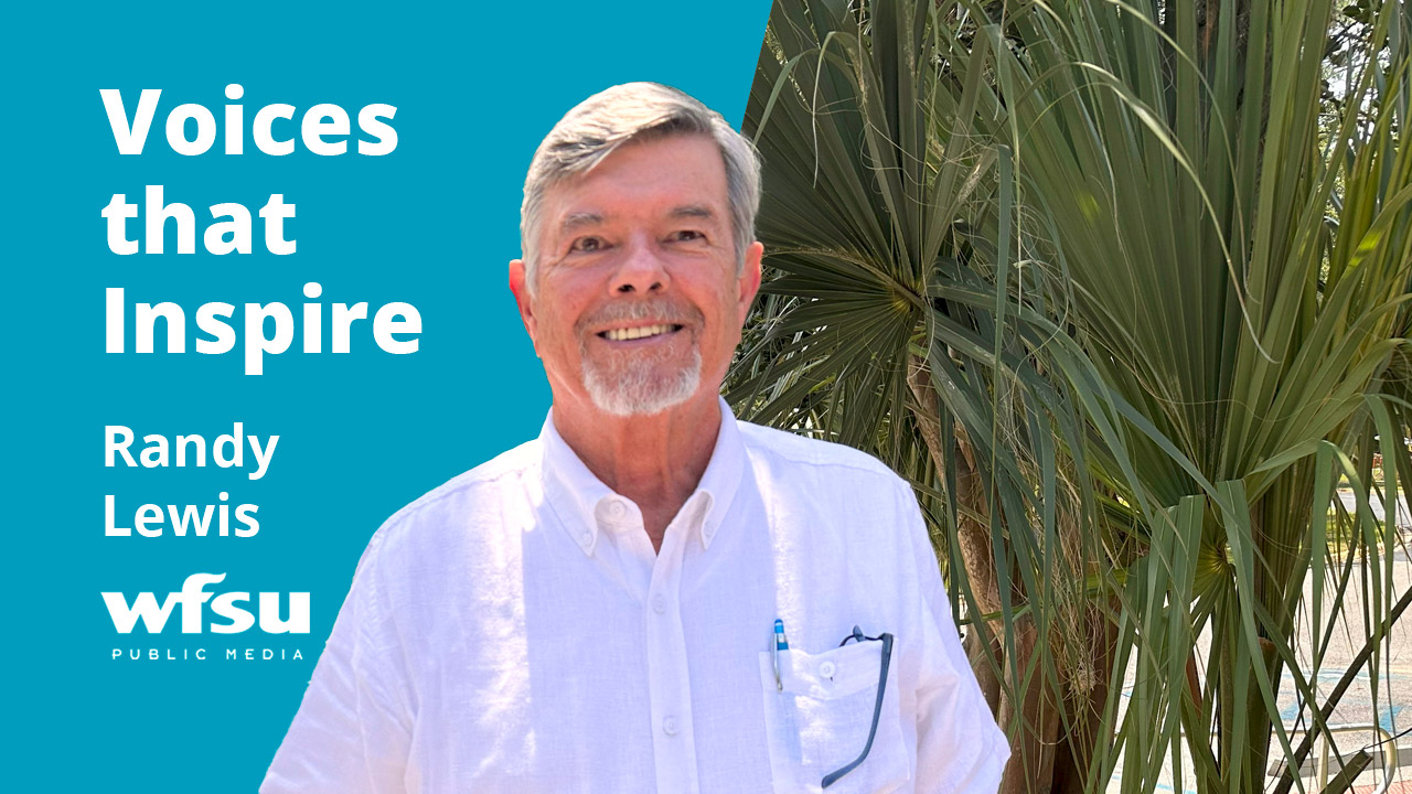 A smiling man in a white shirt stands outside.