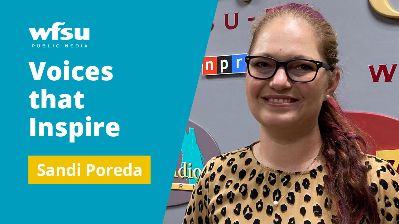 A smiling woman in glasses faces forward.