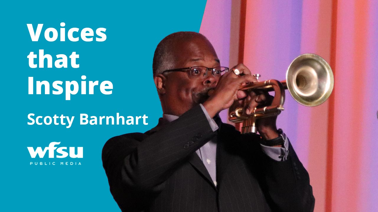 A man in a suit speaks into a microphone.