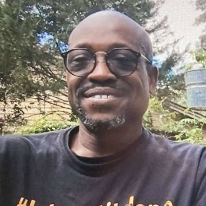 african-american man with glasses sitting in a garden, wearing black t-shirt