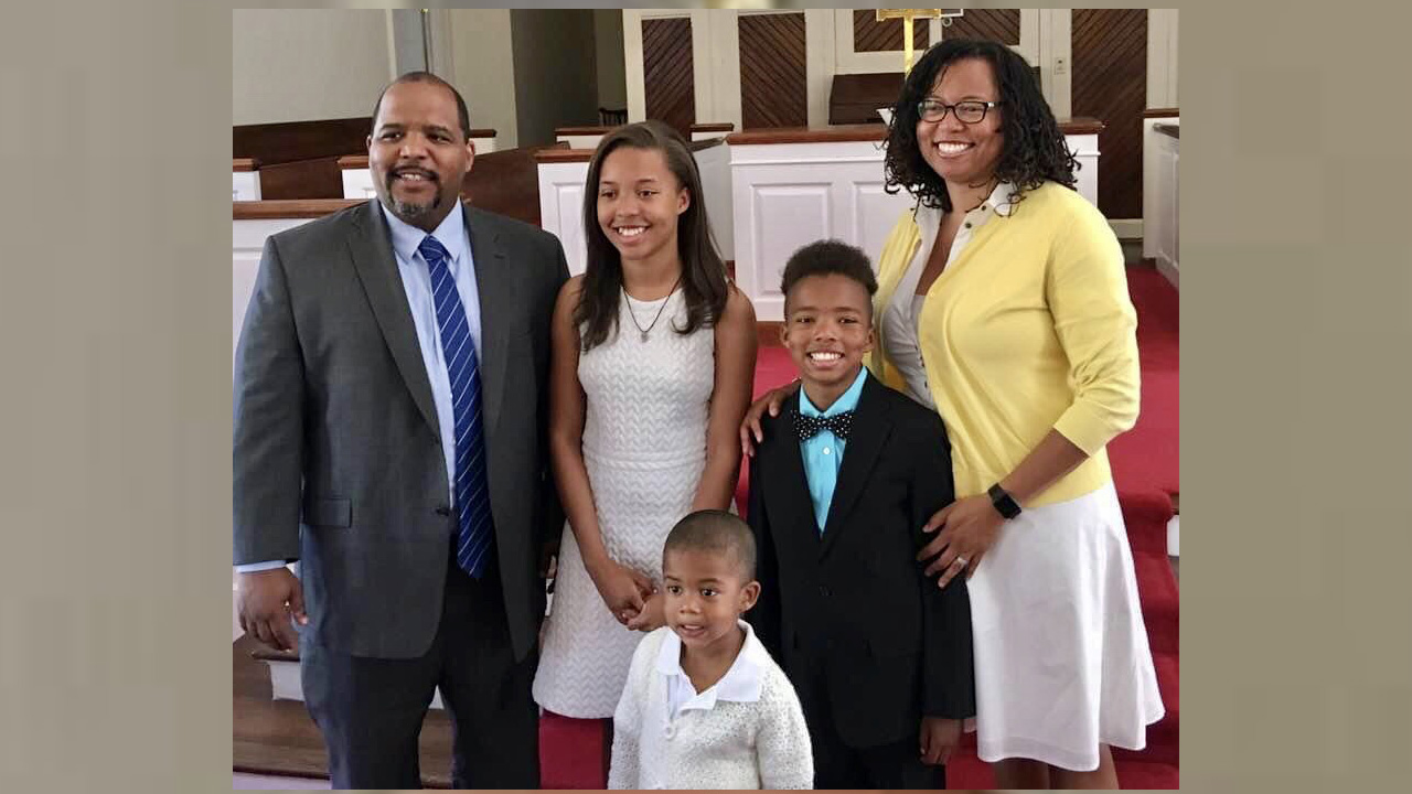 parents, a young girl and two boys standing together at a church
