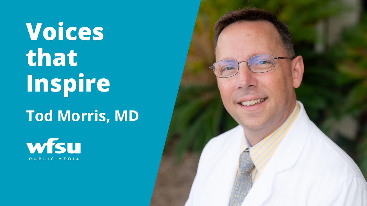 Man smiling in white coat with a shirt and tie.
