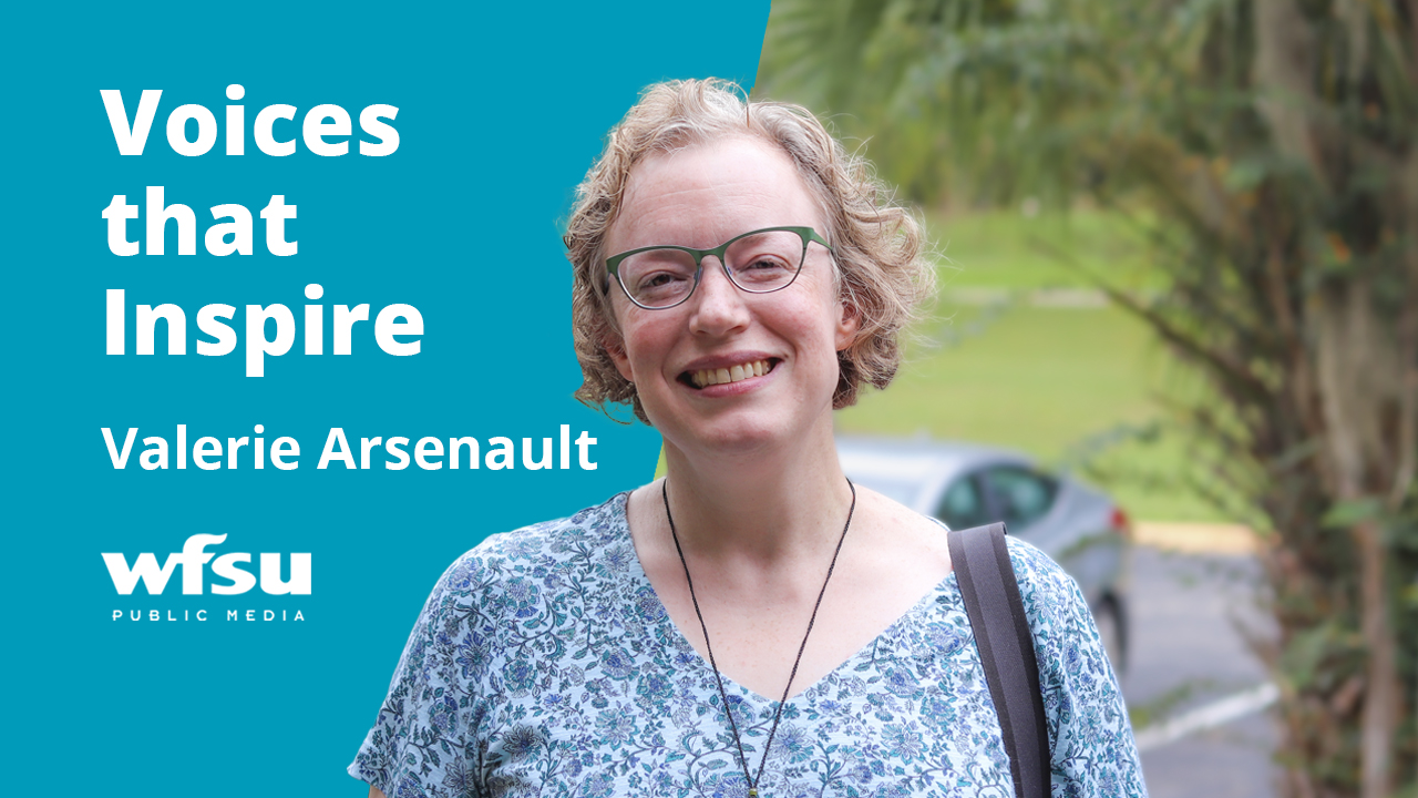 A woman in blue smiles and stares forward.