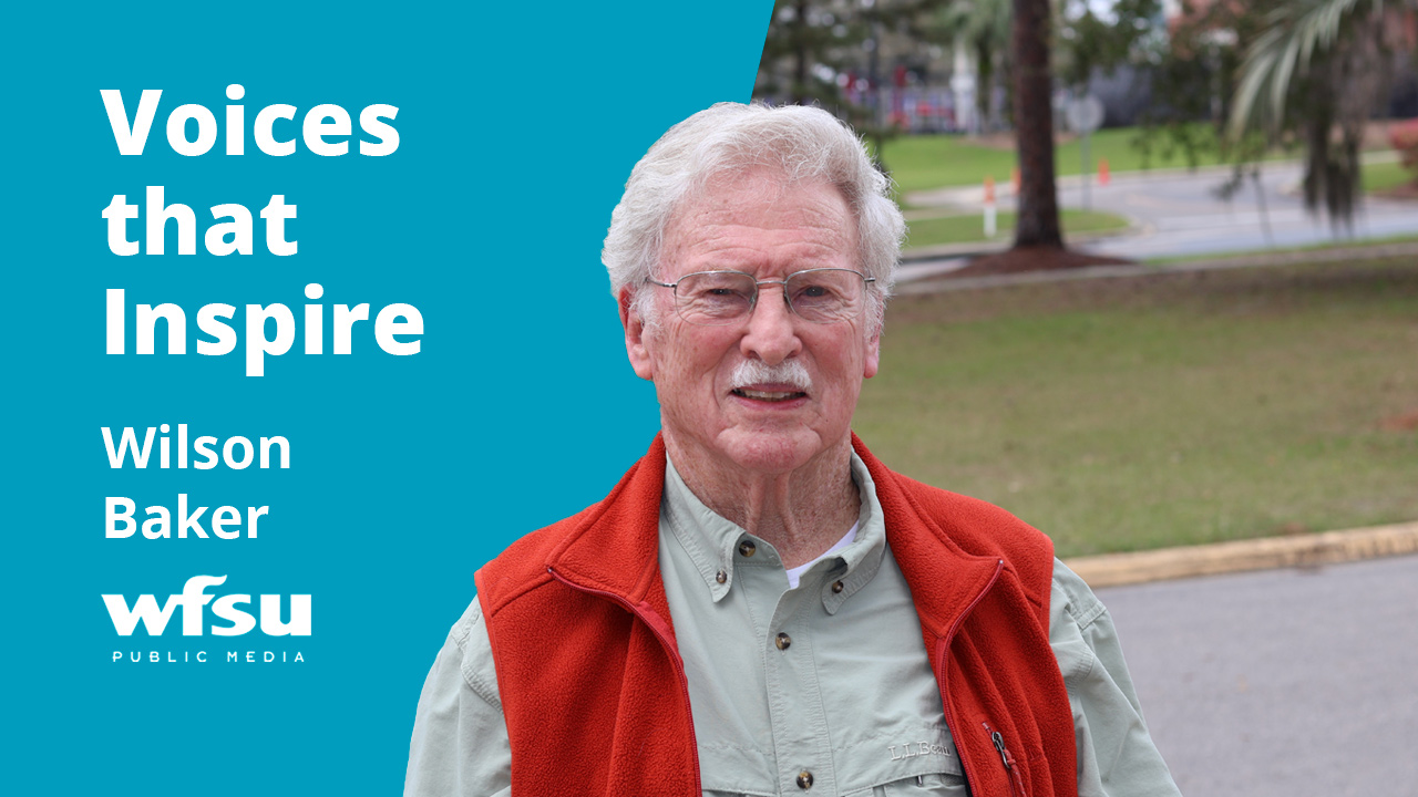 A smiling man stands outside.