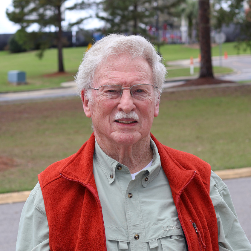 A smiling man stands outside.