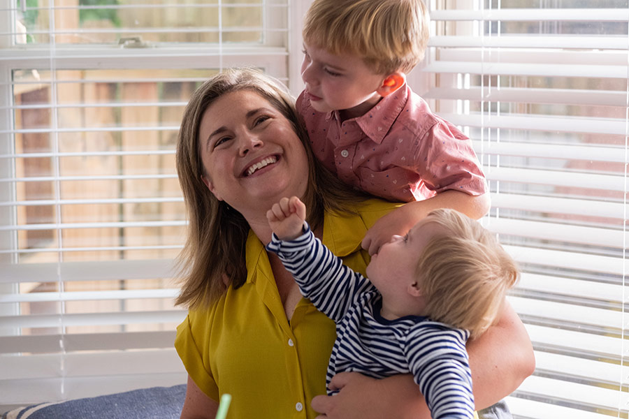 a mom holding her two young children, smiling