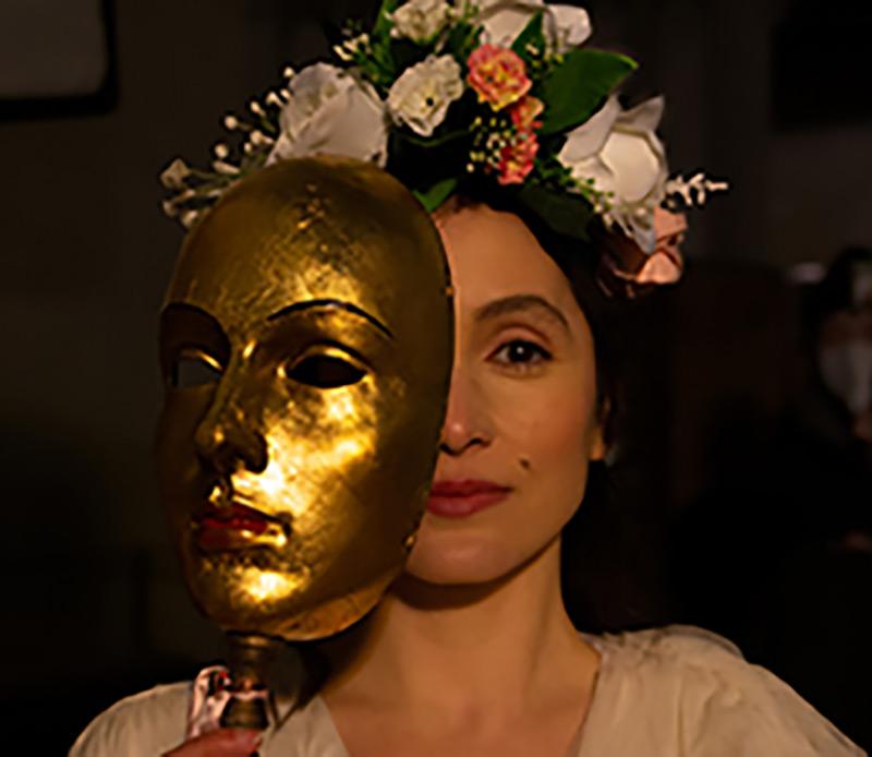 face of woman, flowers in hair, half behind golden mask