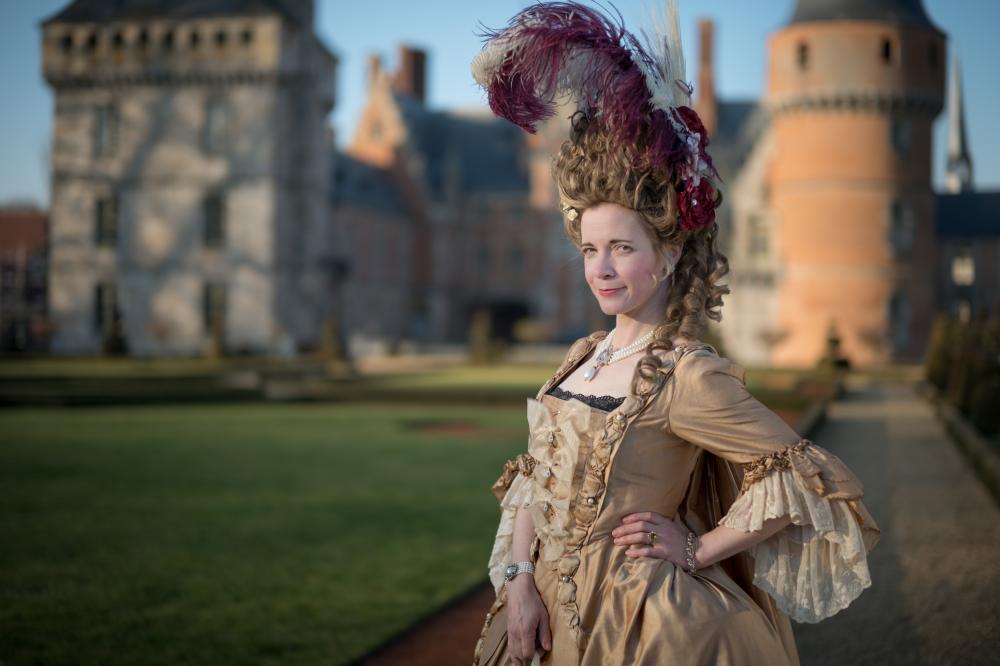 A queen standing in front of a castle