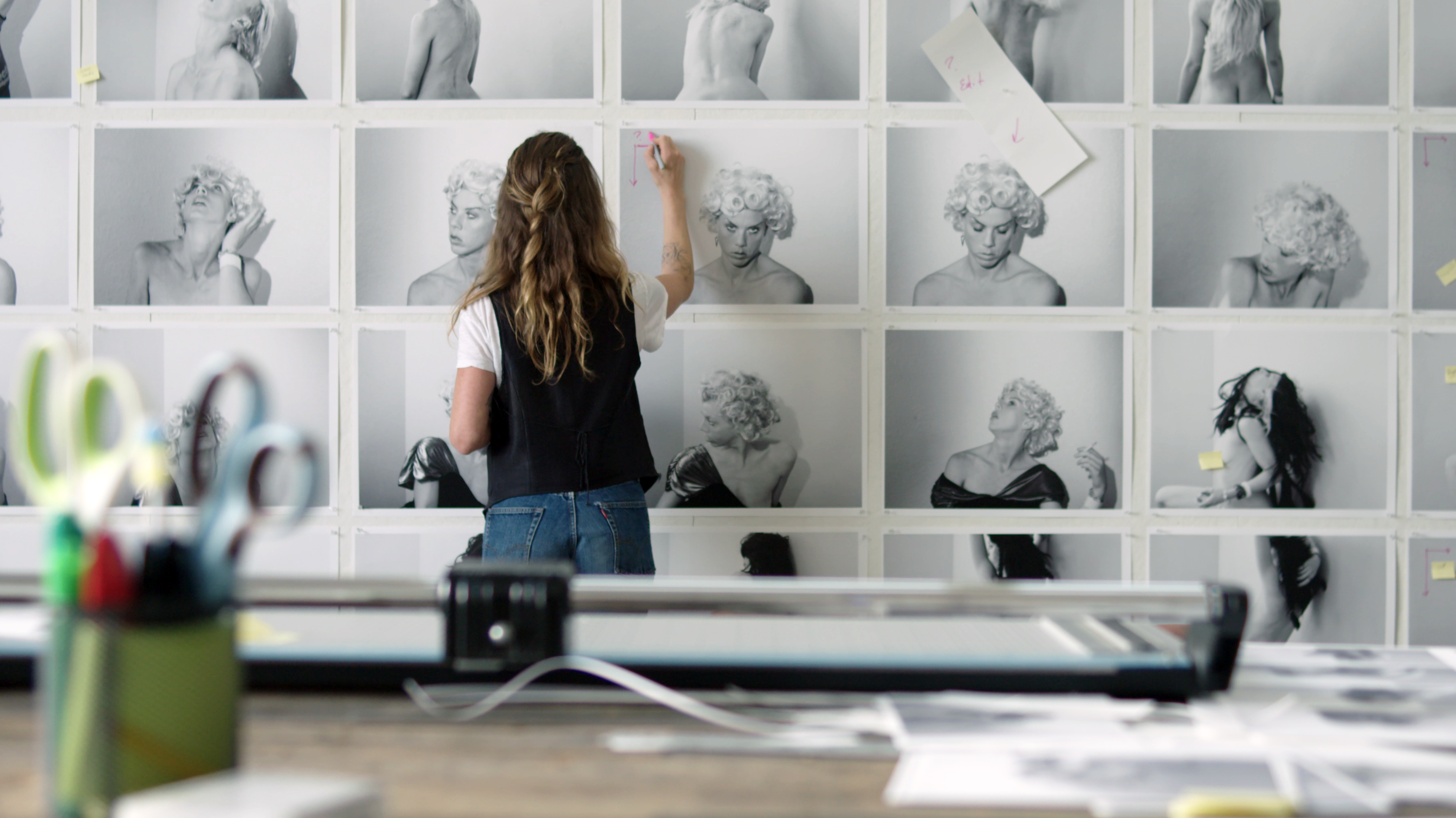 woman marking photos of a woman posted on a wall
