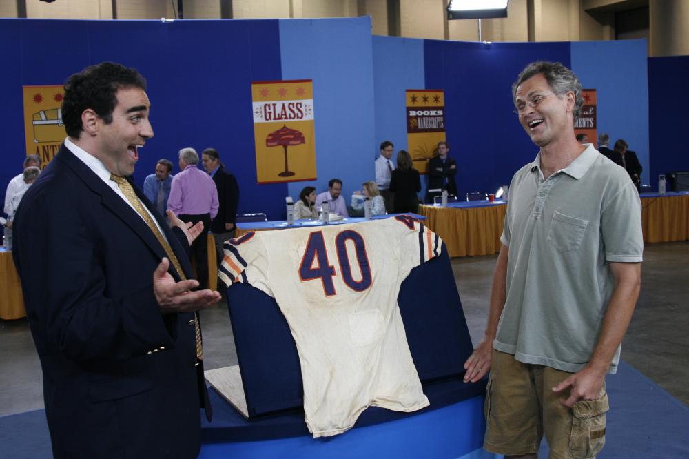 Two men beside a sports jersey on display