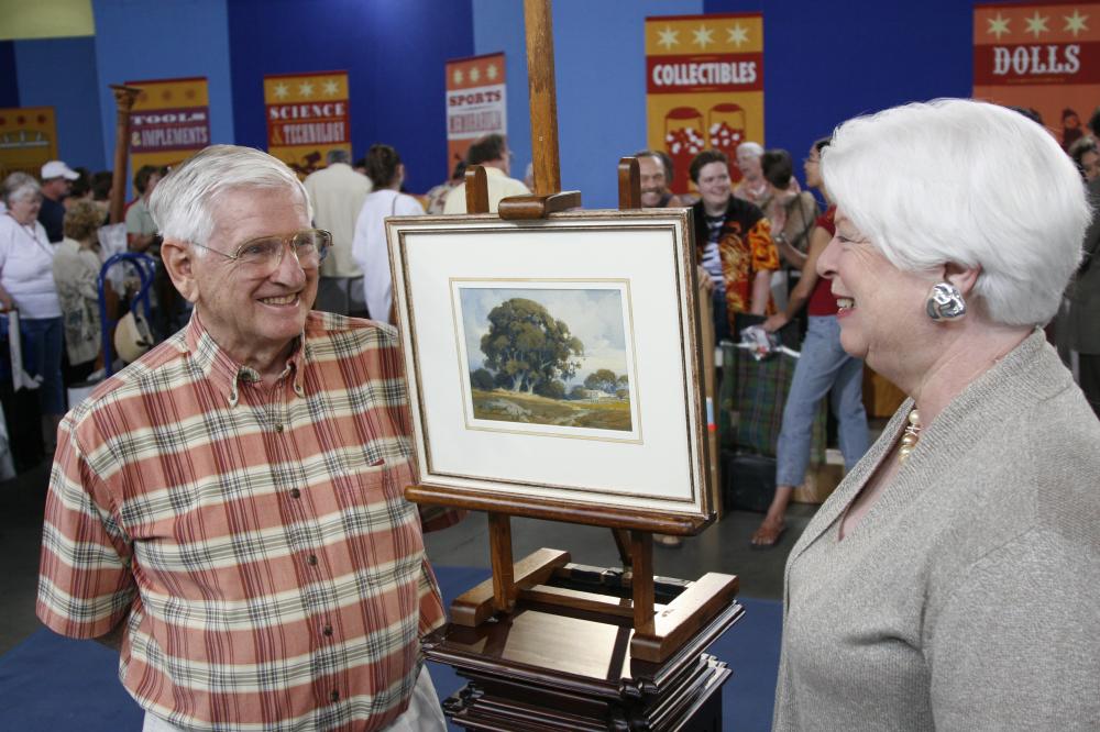 Two people by a painting at an auction