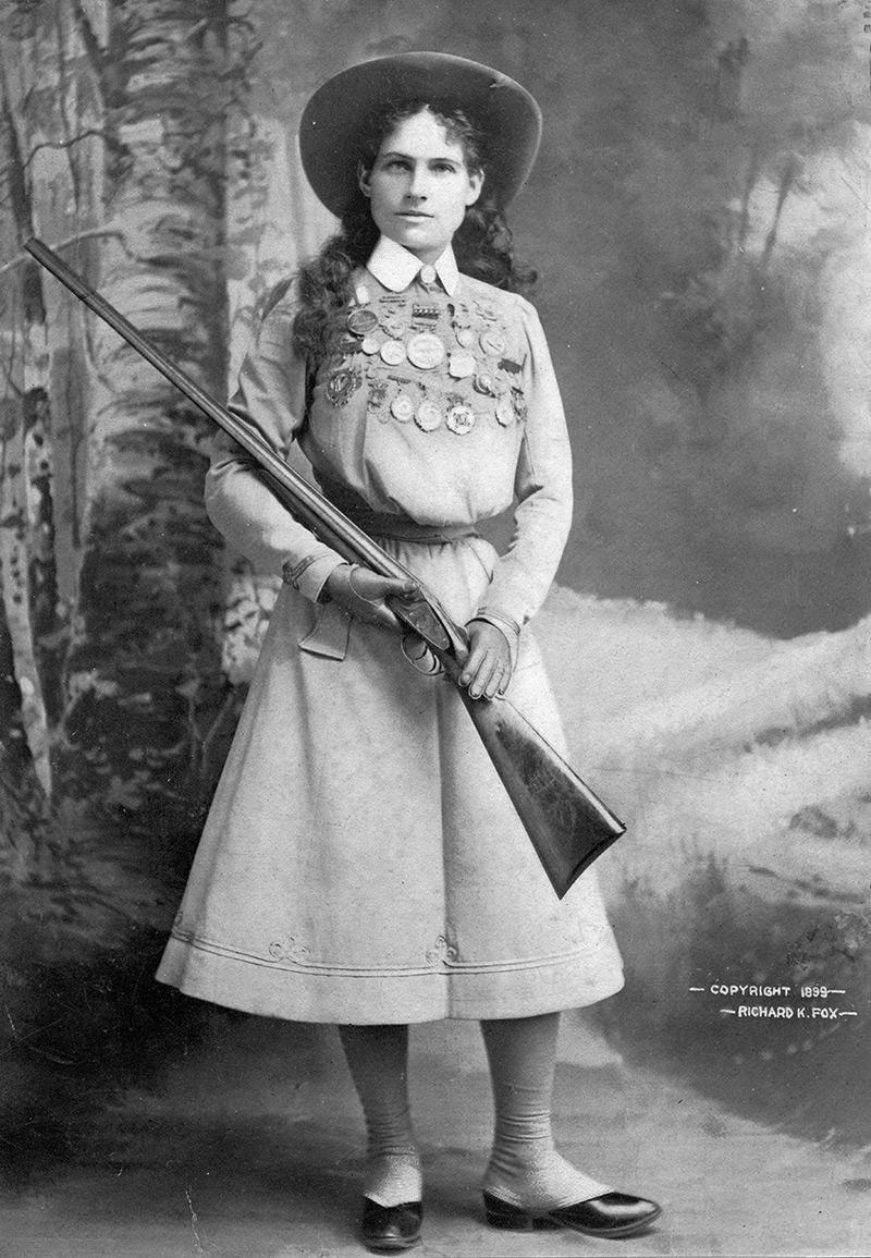 very old black and white photo of a woman with a rifle
