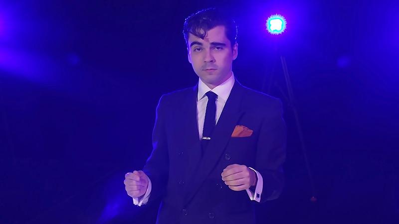 male performer in suit on blue-lit stage