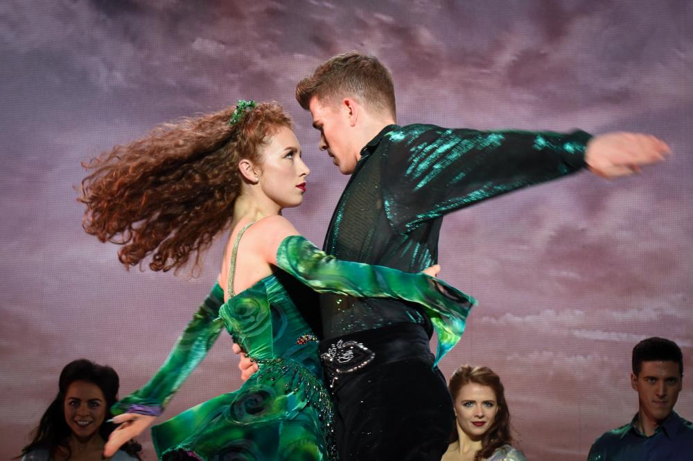 female and male dancer embracing, in green