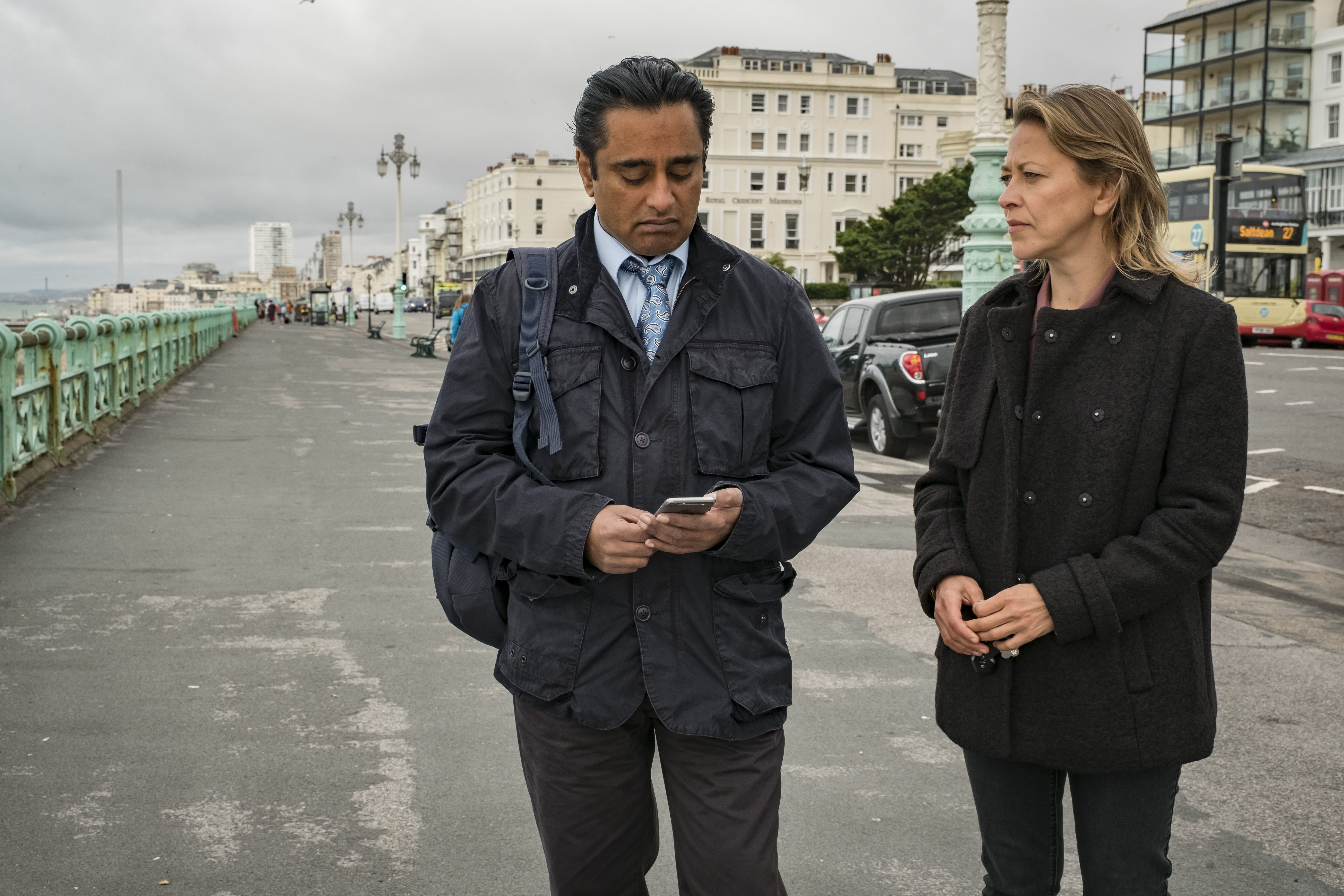 man, looking at cell phone, and women stand in European street talking