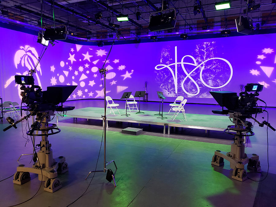 tv studio lit up with studio lighting and t-s-o written in light on the curtain backdrop.