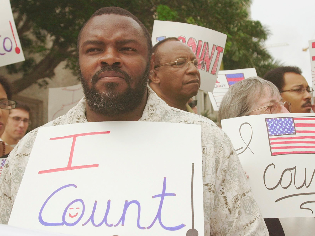 man holding sign that say 'i count' at a rally