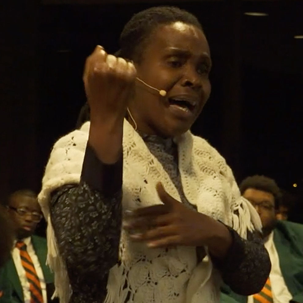 woman with shawl passionately speaking in front of famu choir