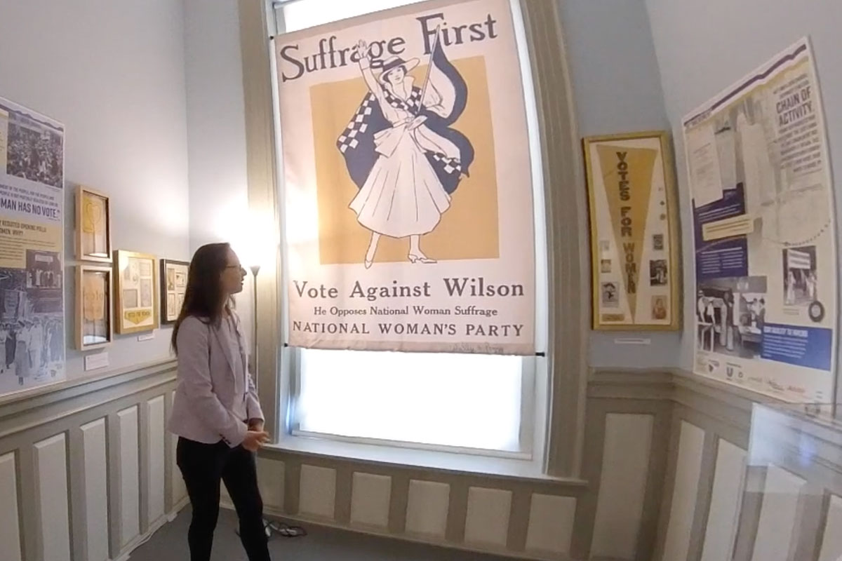woman looking at suffrage first banner, an exhibit in old Florida capitol